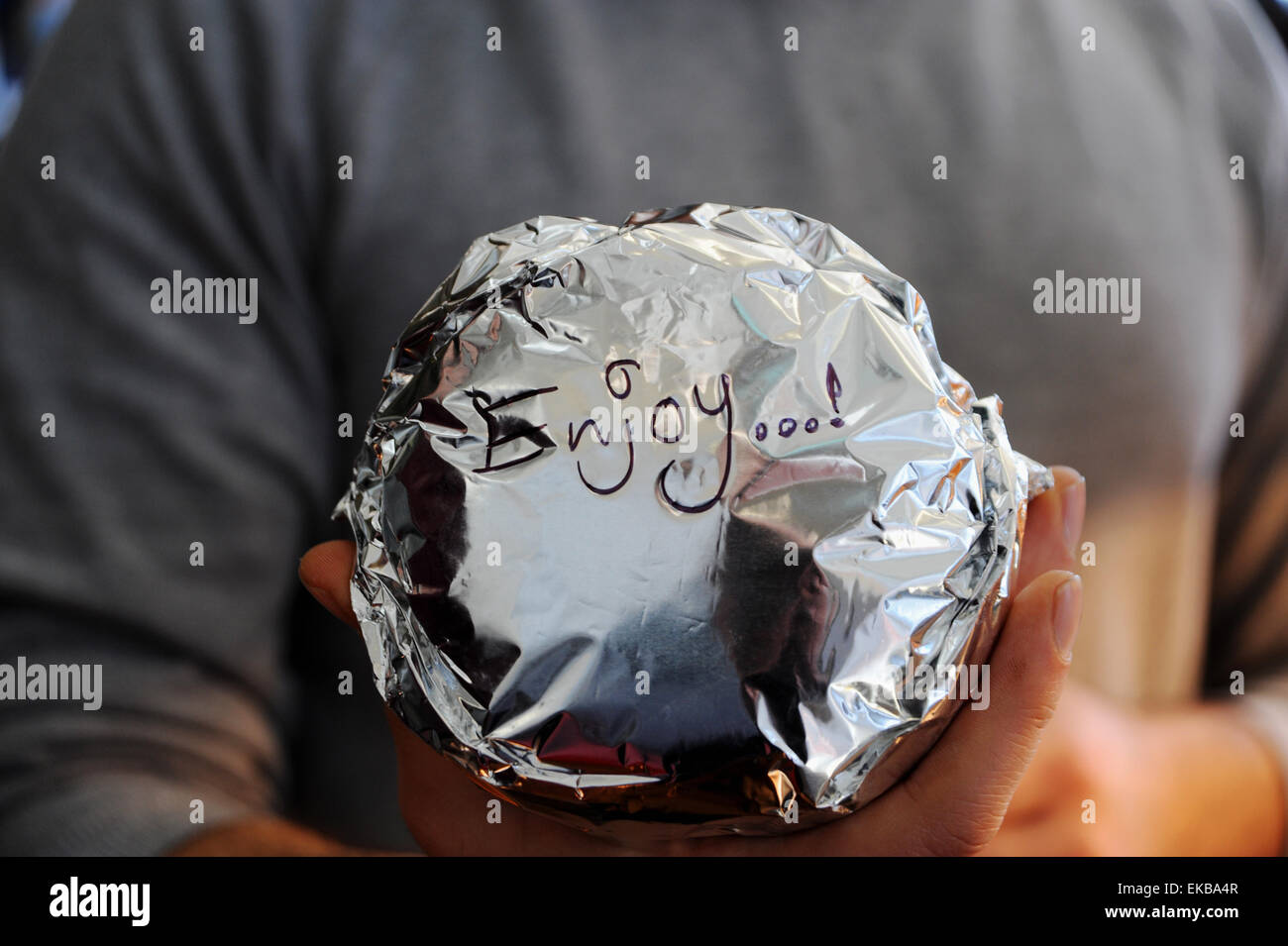 Enjoy a freshly made take away burger wrapped in tin foil ready to serve at a take away shop Stock Photo