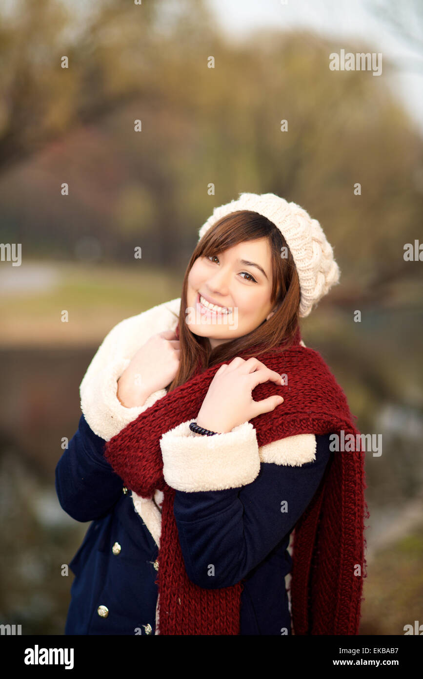 Beautiful mixed race girl smiling in a park in Winter clothes Stock Photo