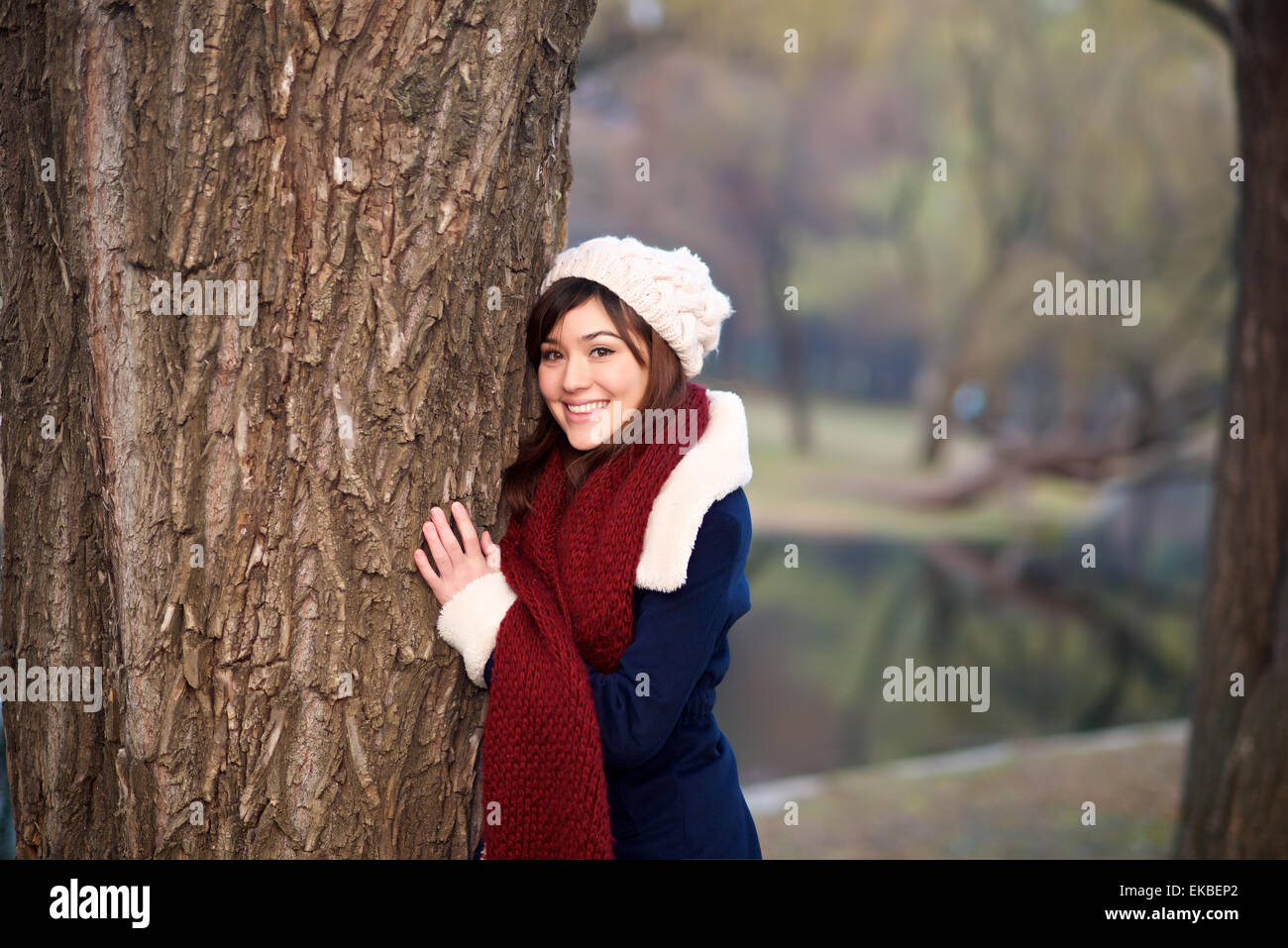 Beautiful mixed race girl hugging tree in a park in Winter Stock Photo