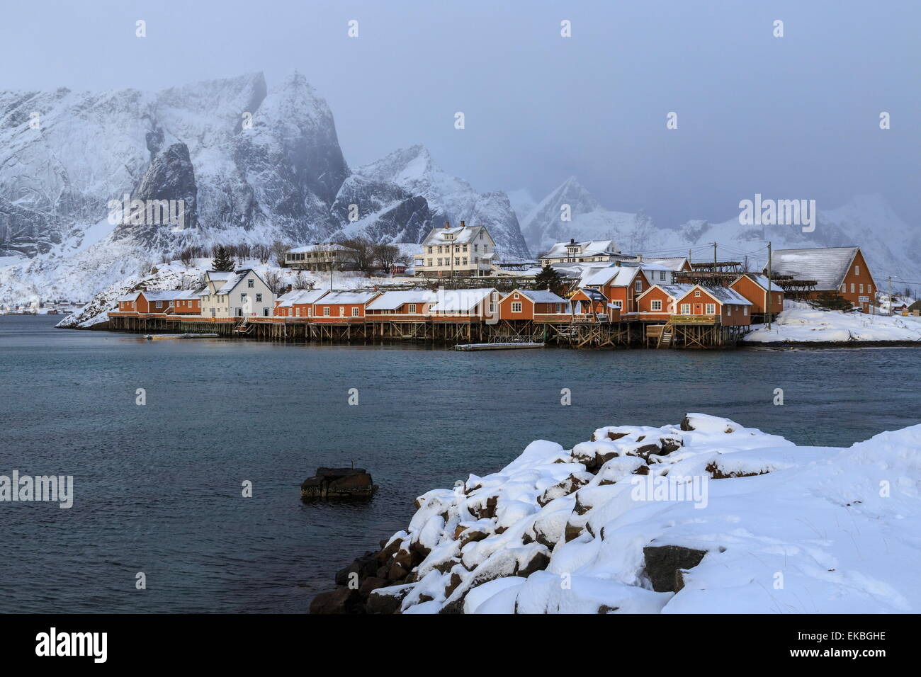 Snowy peaks and rorbu, the red houses of fishermen, in the landscape of the Lofoten Islands, Arctic, Norway, Scandinavia, Europe Stock Photo