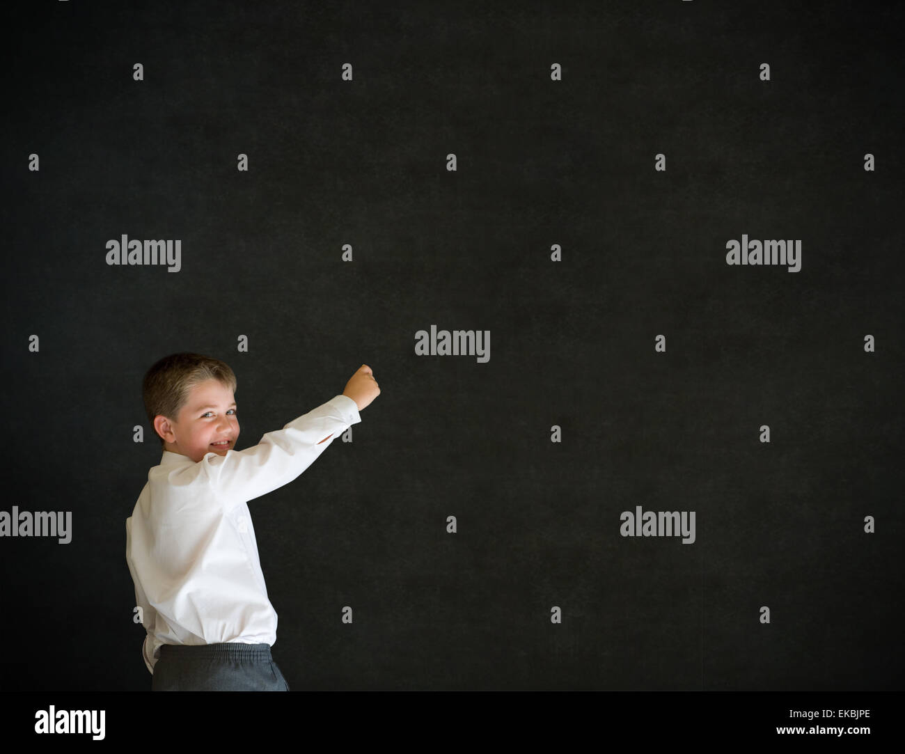 Boy dressed up as businessman writing on blackboard Stock Photo