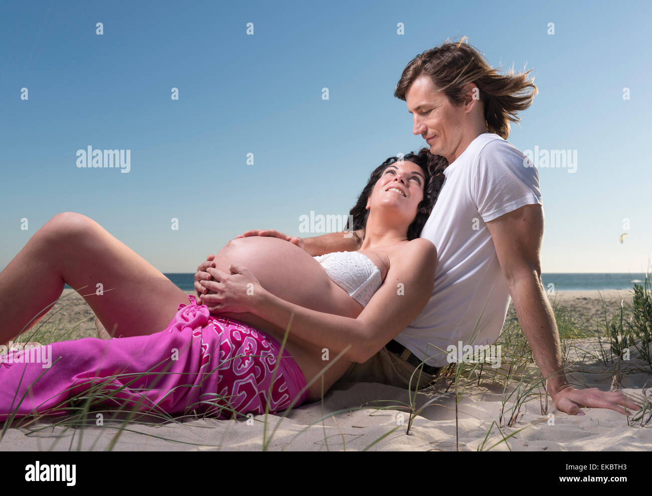 Pregnant couple relaxing at the beach. Stock Photo