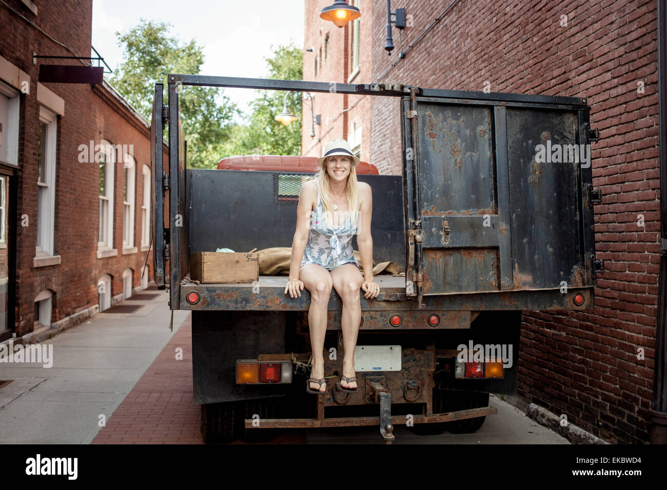Woman sitting on a farmer's organic food truck outside grocery store Stock Photo