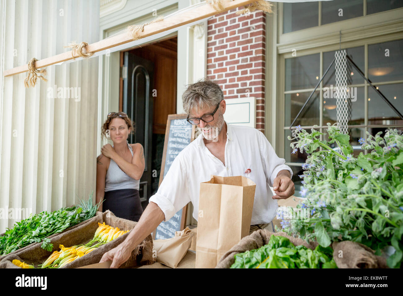 Farmer selling organic food on stall outside store Stock Photo