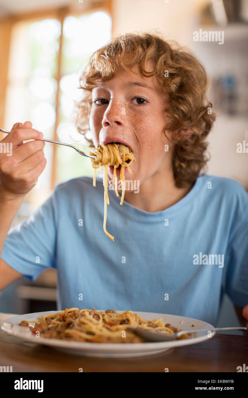 Teenage boy eating spaghetti at dining table Stock Photo