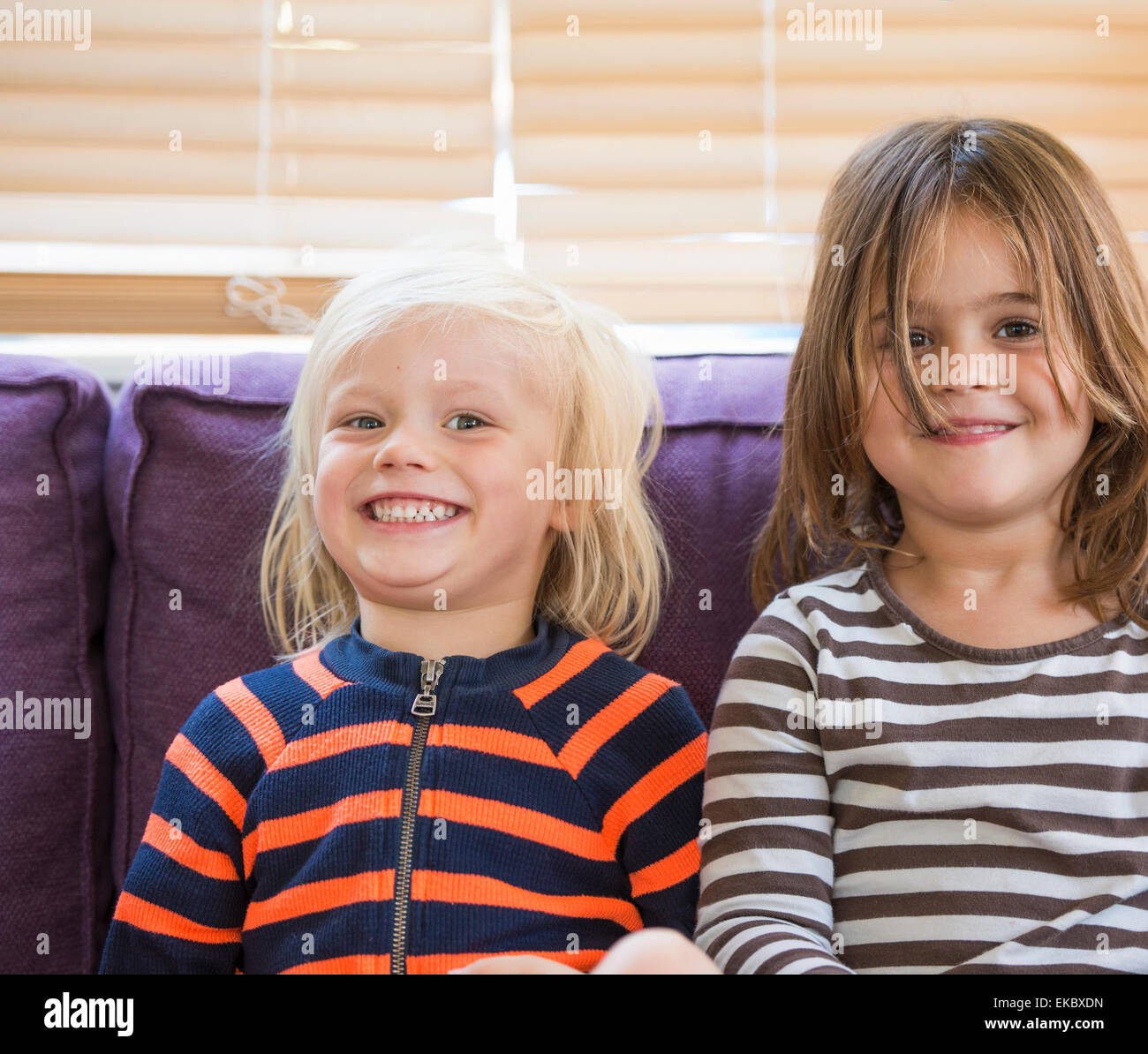 Portrait of young boy and girl, sitting on sofa, smiling Stock Photo