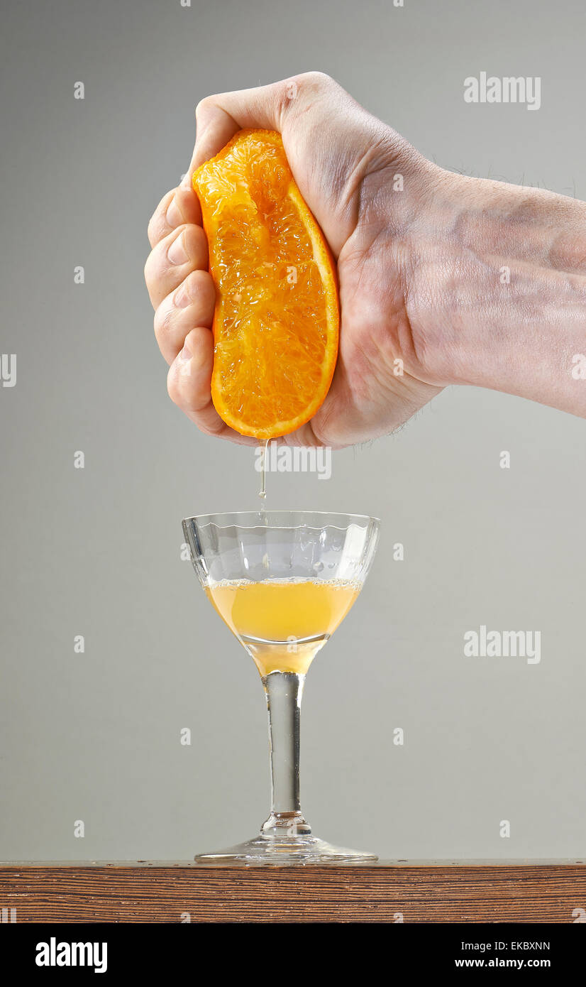 Fresh Squeezed Orange Juice by male hand and juice falling in a elegant