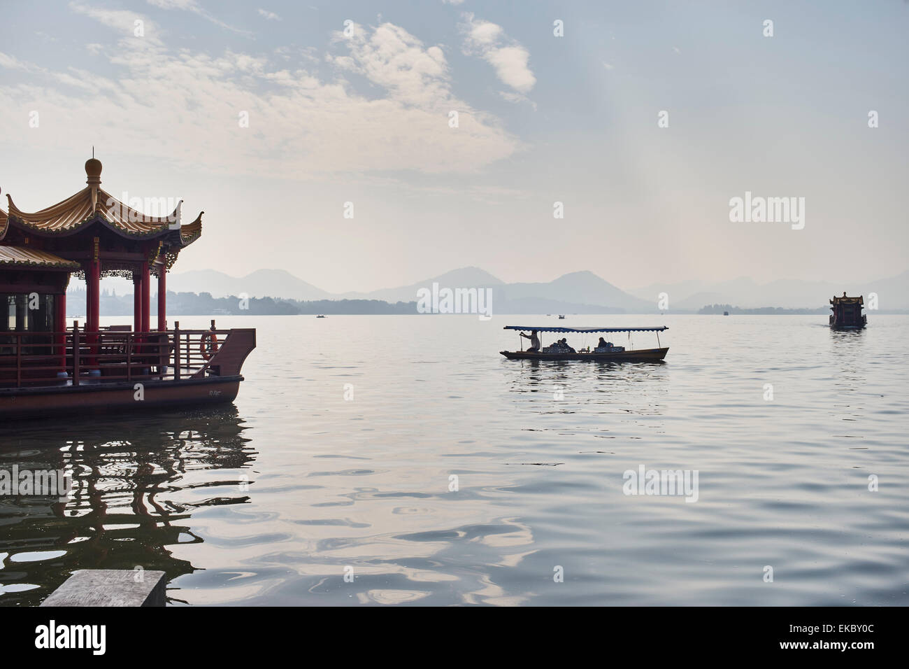 View of silhouetted fishing boat and lakeside restaurant on Westlake, Hangzhou, China Stock Photo