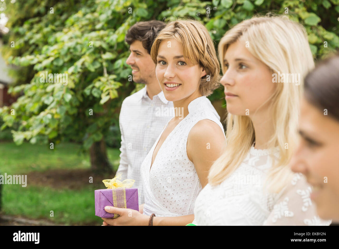 Portrait of young man and three women holding birthday gift in garden Stock Photo