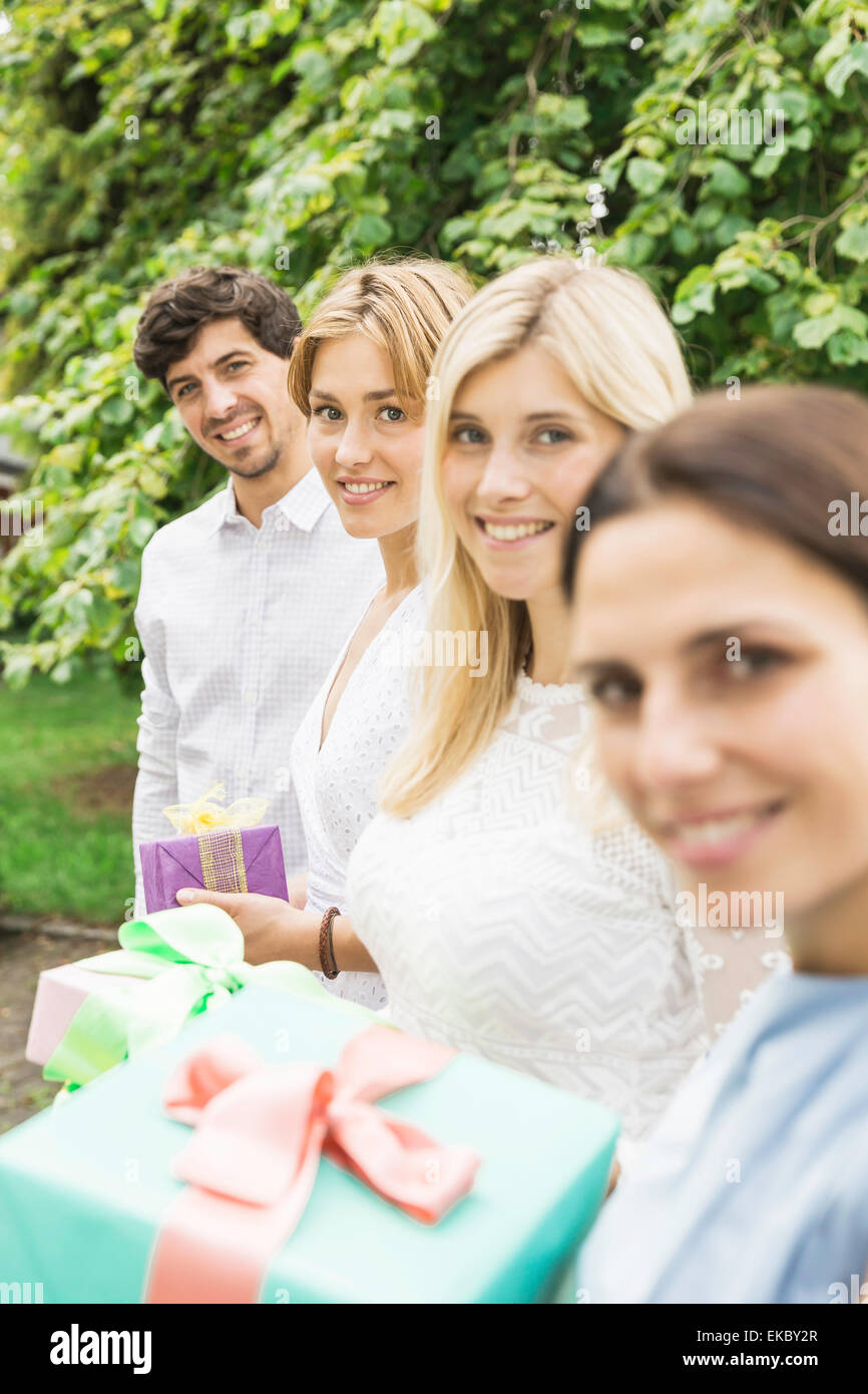 Portrait of young man and three women holding birthday gifts in garden Stock Photo