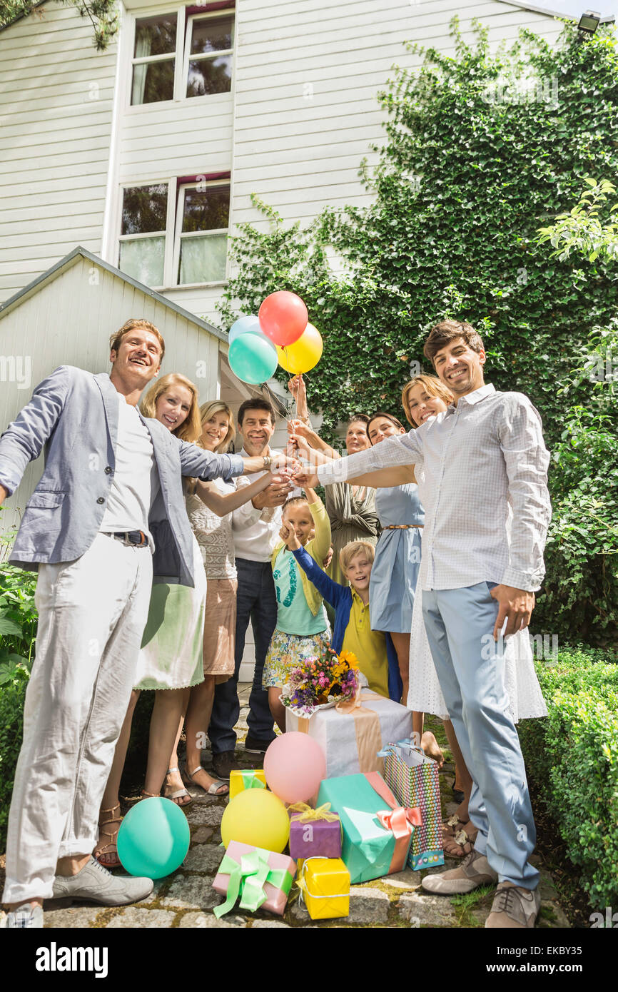 Portrait of three generation family holding up birthday balloons in garden Stock Photo