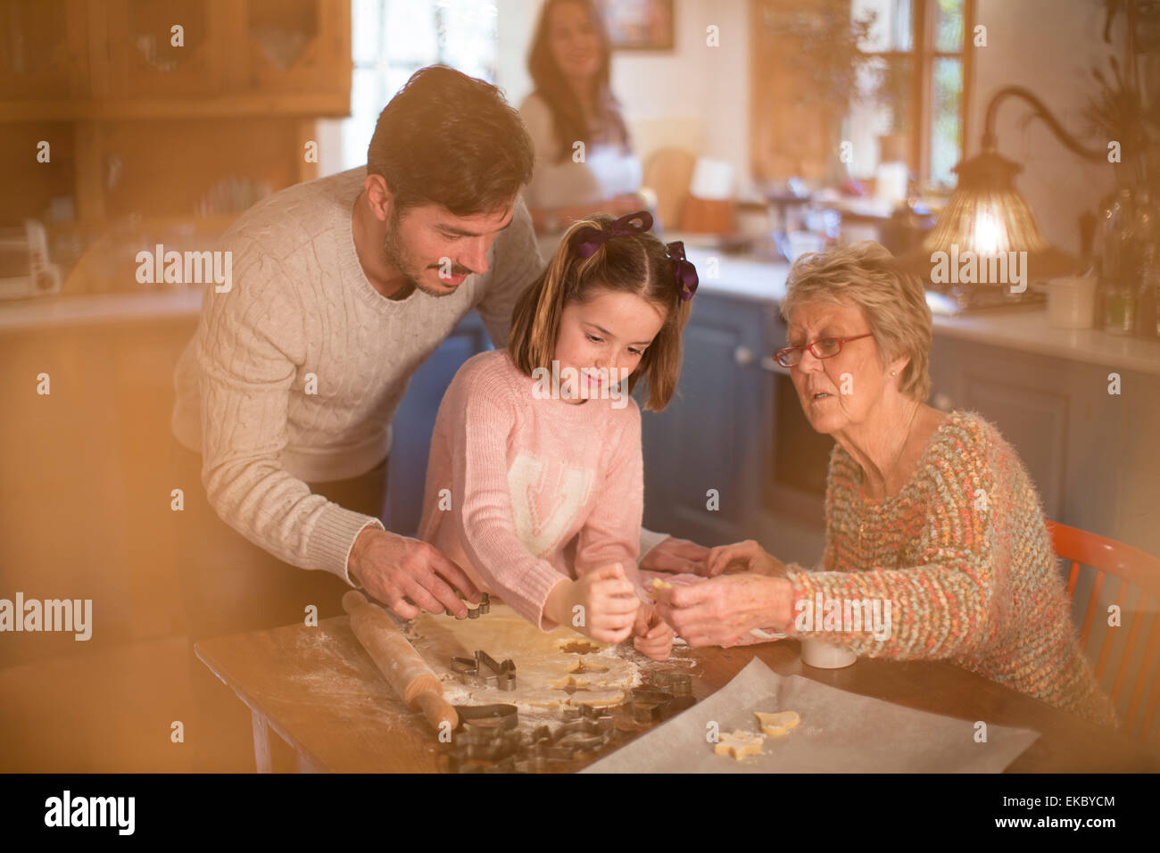 Three generation family cutting shapes in dough to make homemade cookies Stock Photo