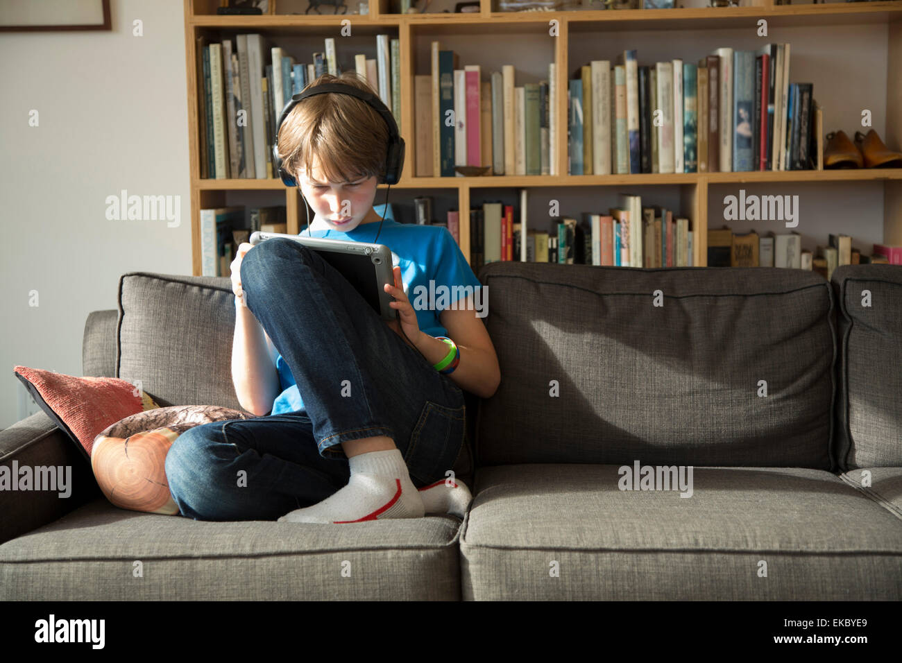 Boy listening to music on headphones and using digital tablet Stock Photo