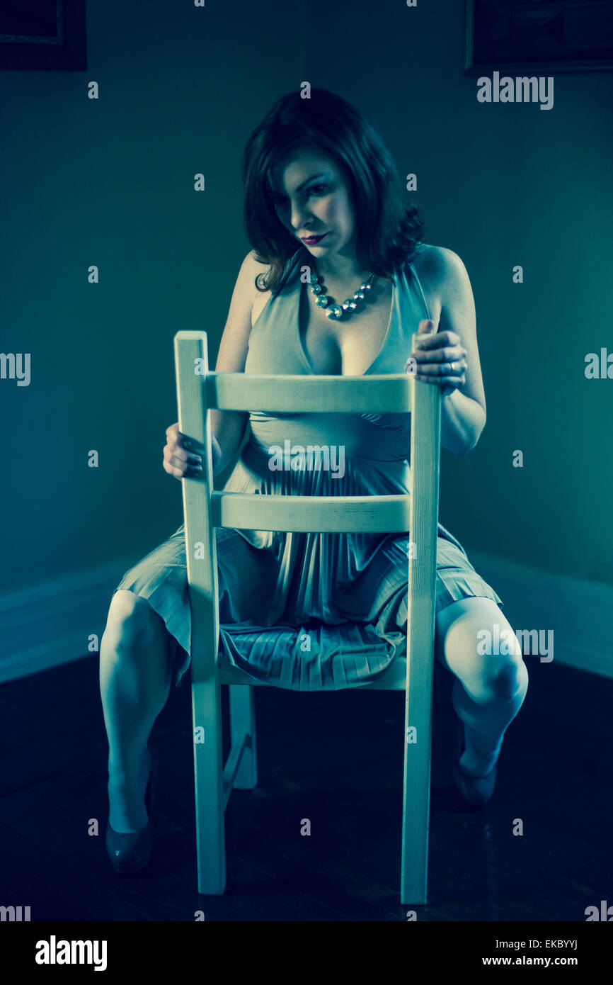 Portrait of mid adult woman, straddling chair Stock Photo