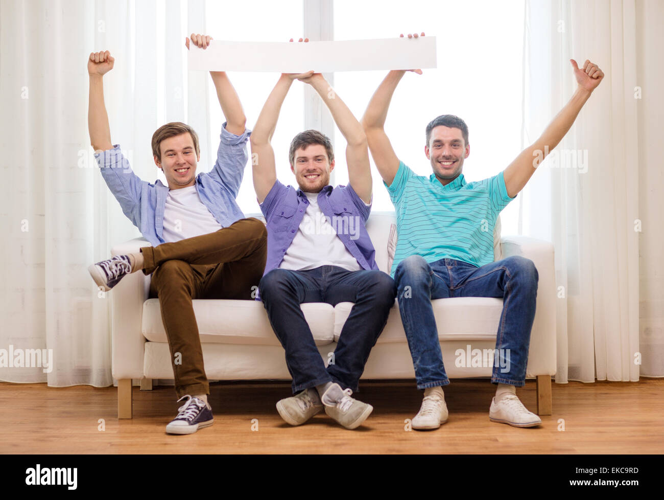 smiling male friends holding white blank banner Stock Photo