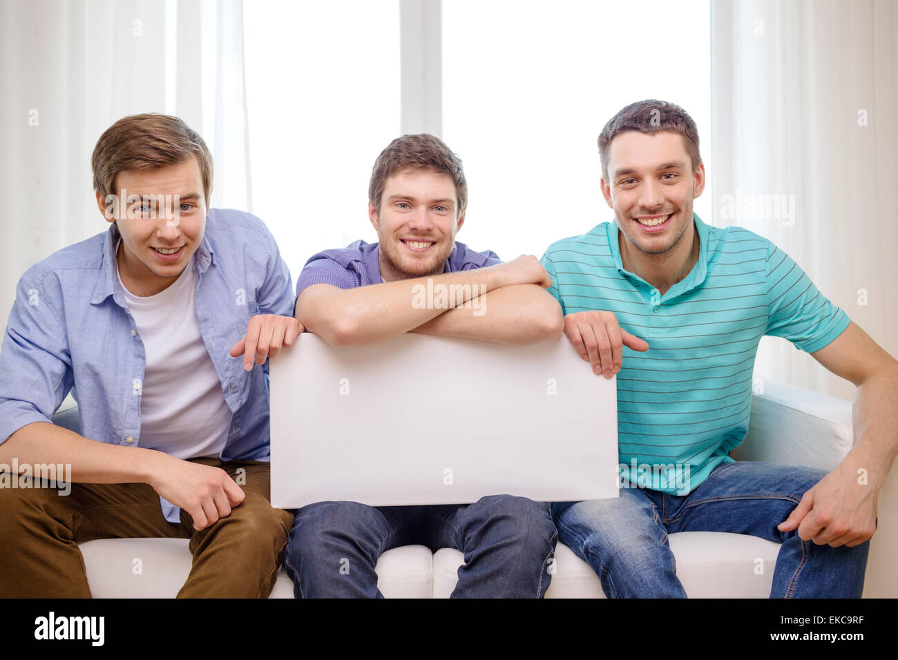 smiling male friends holding white blank board Stock Photo