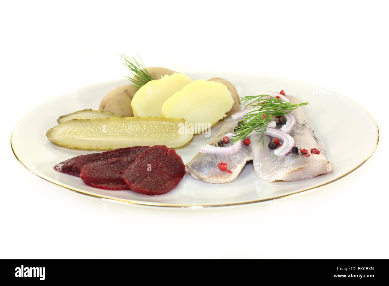 a plate of pickled herring fillet, boiled potatoes, beetroot and pickled gherkins Stock Photo