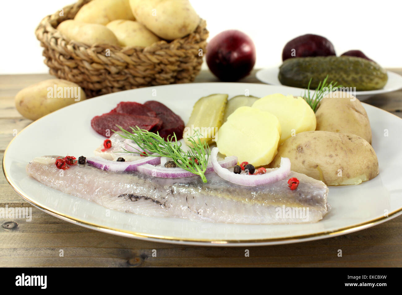 a plate of pickled herring fillet, boiled potatoes, beetroot and pickled gherkins Stock Photo