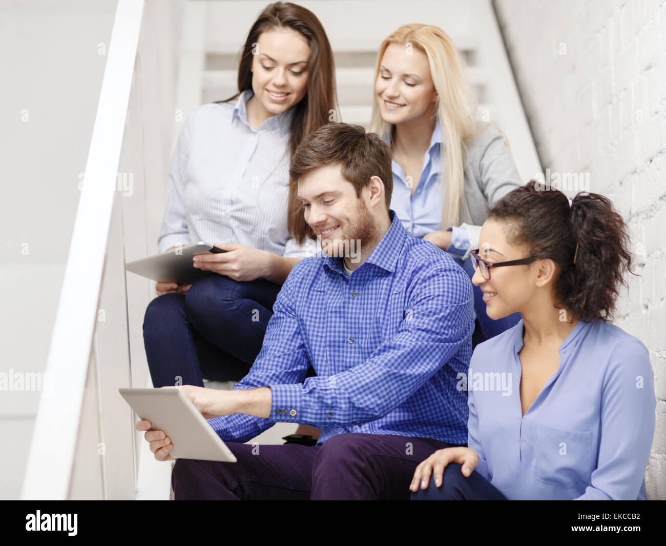 team with tablet pc computer sitting on staircase Stock Photo
