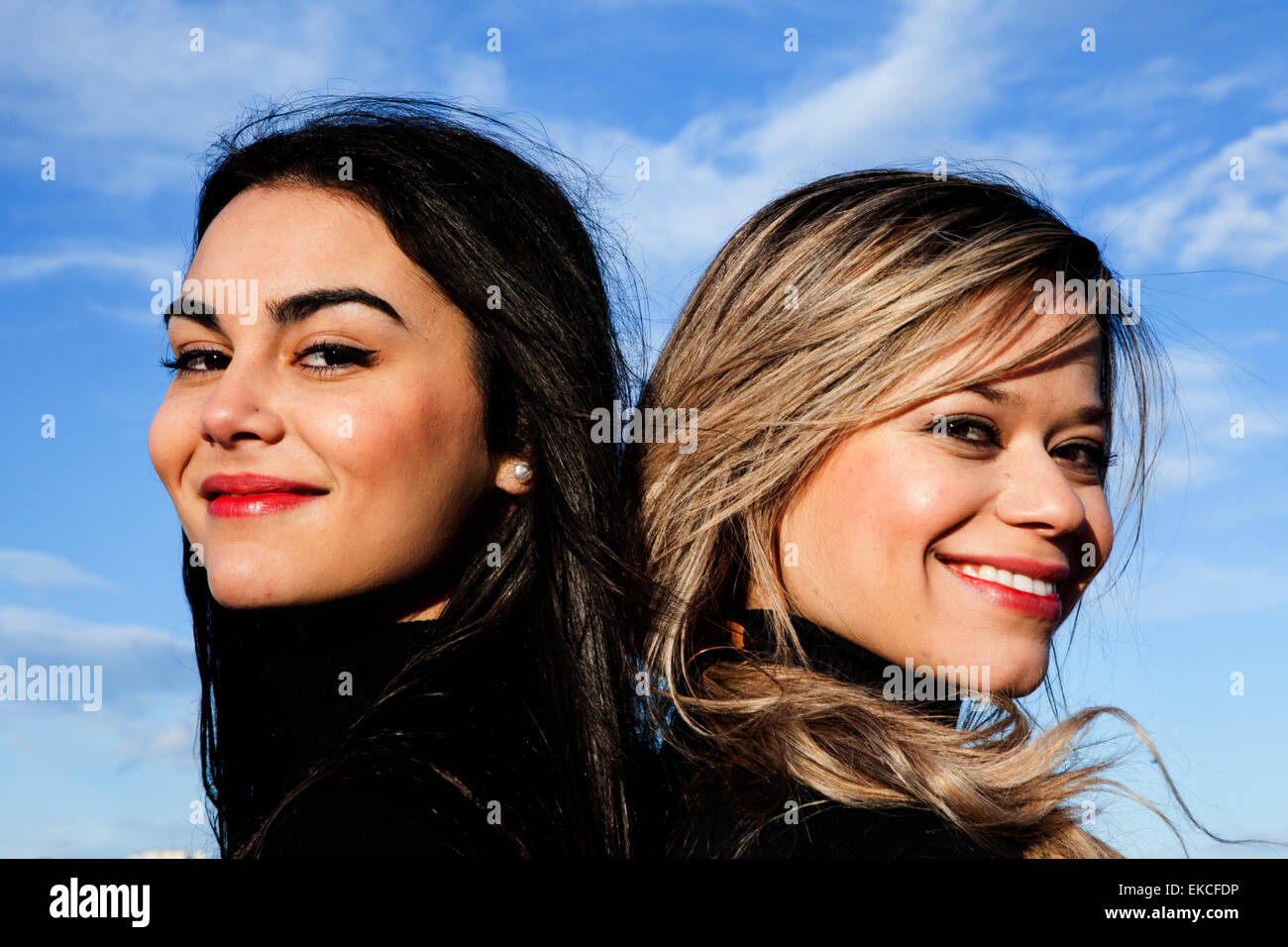 Portrait of two beautiful women standing back to back Stock Photo