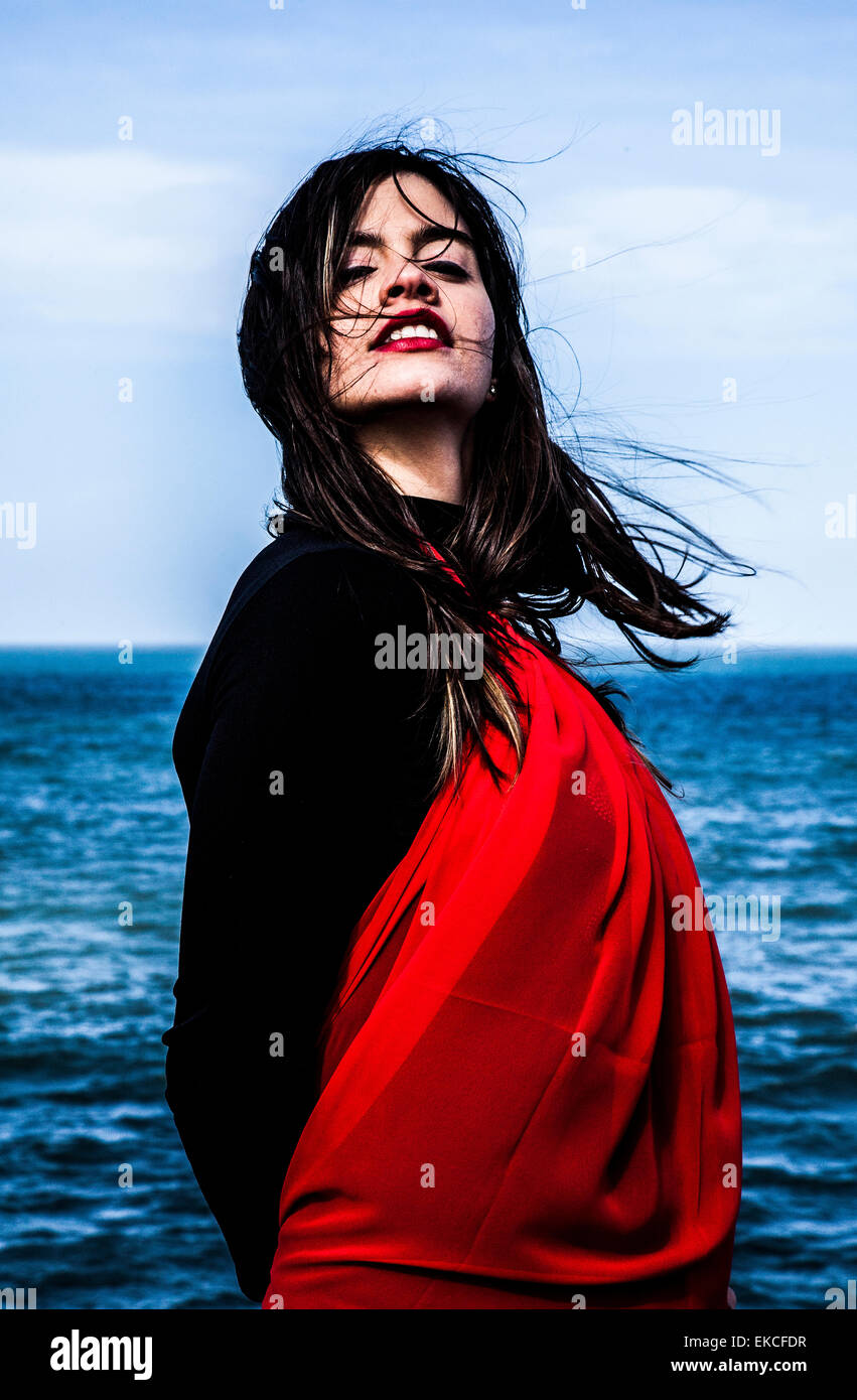 Portrait of a beautiful woman standing by the sea Stock Photo - Alamy