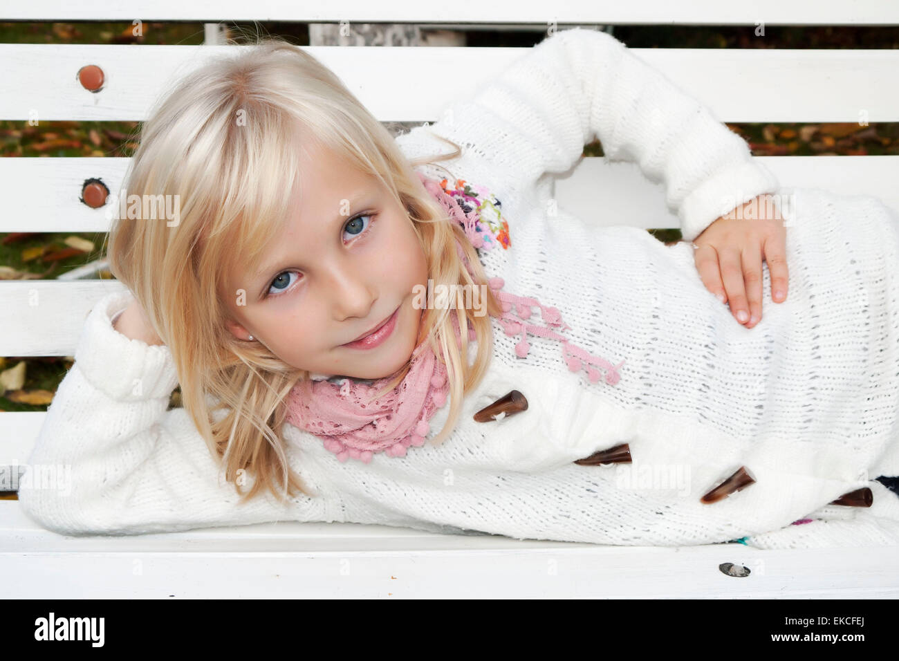 Smiling girl lying on a bench with her hand on her hip Stock Photo