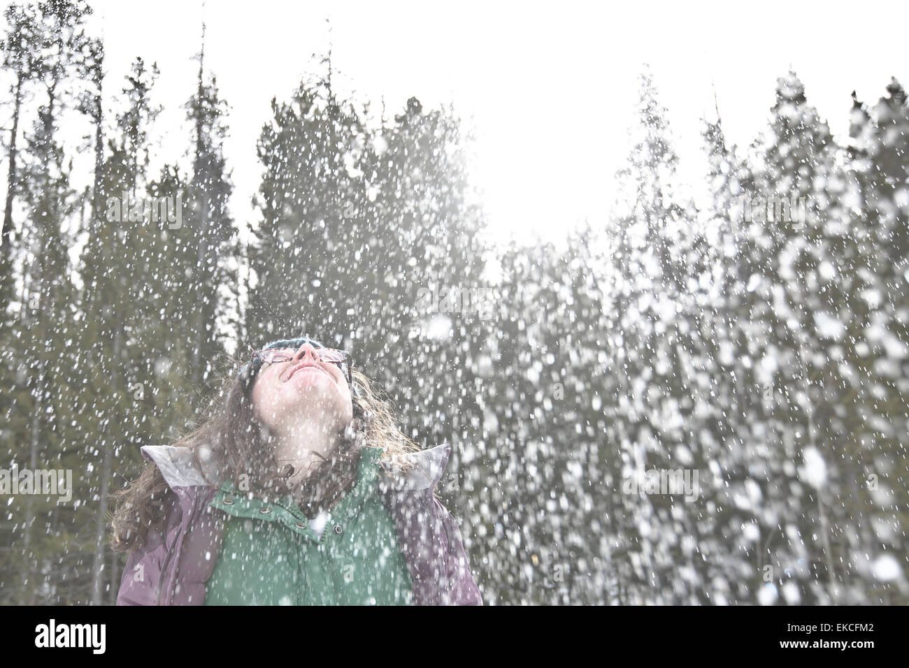 Woman in the snow throwing her head back and laughing Stock Photo