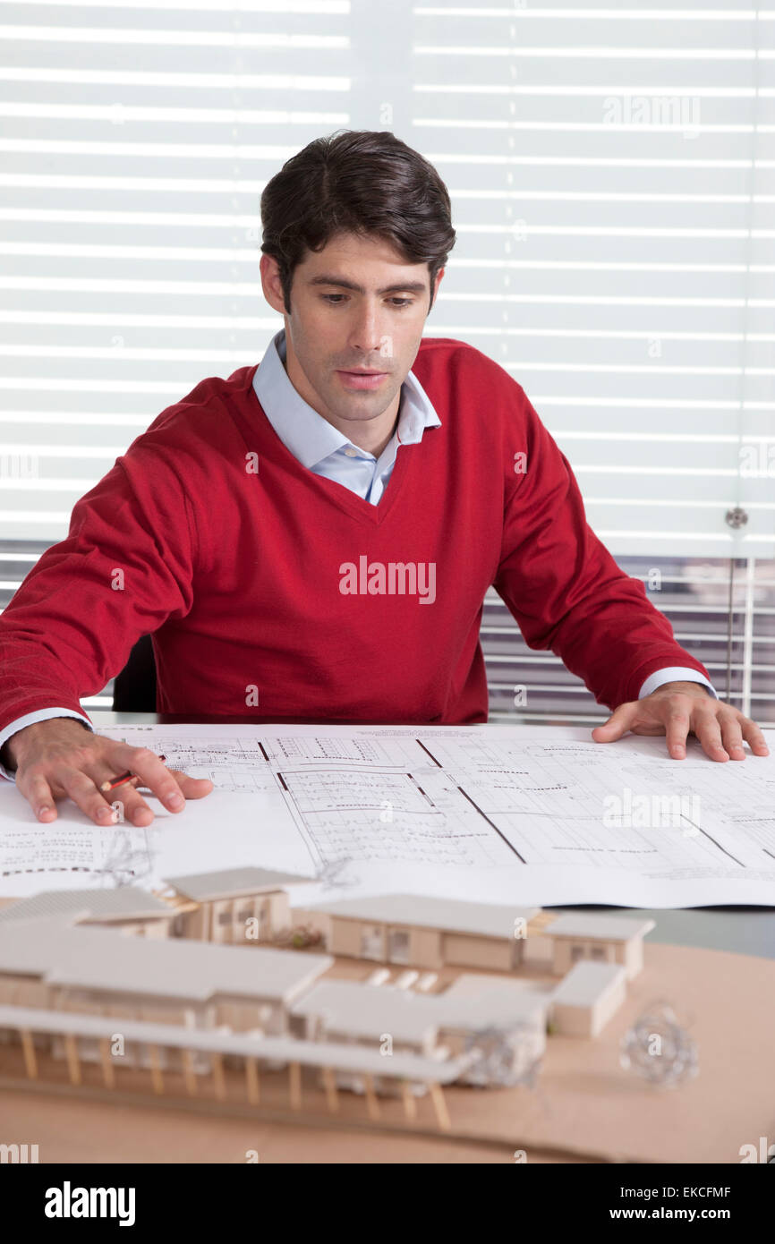 Architect At Desk Looking At Plans And Building Model Stock Photo