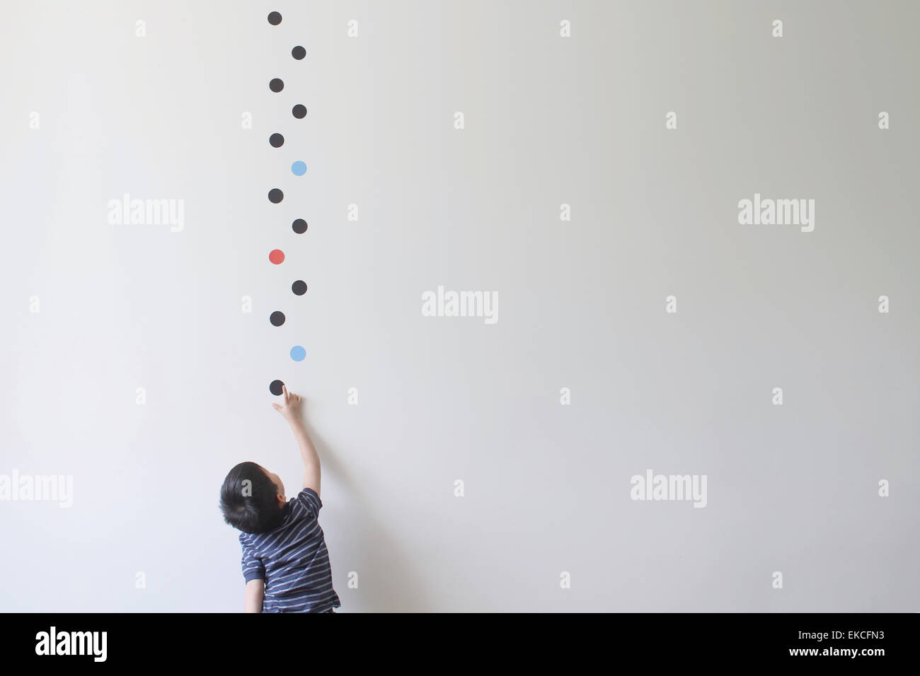 Boy trying to pick a dot off a wall Stock Photo