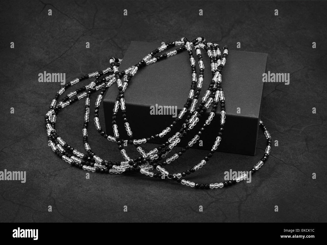 Black and white beads on the cracked dark gray background. Stock Photo