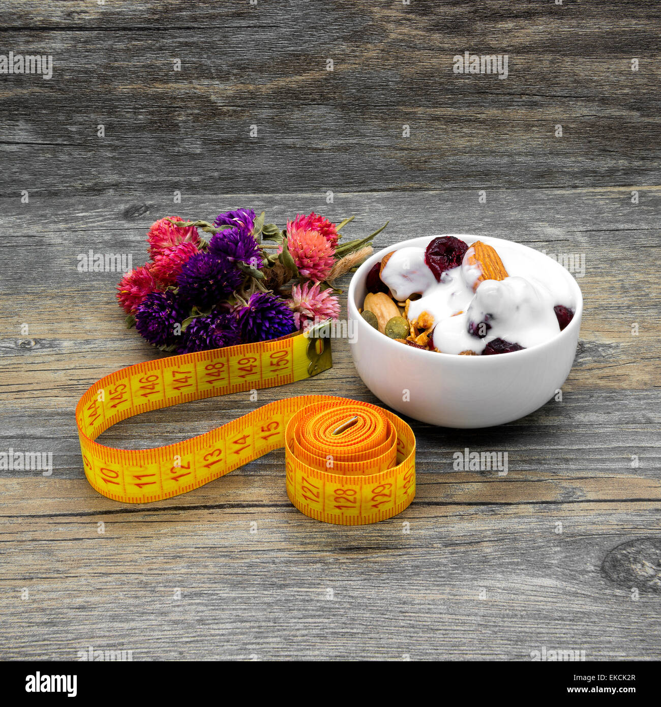 Centimeter and granola with yogurt on rustic wooden background. Stock Photo