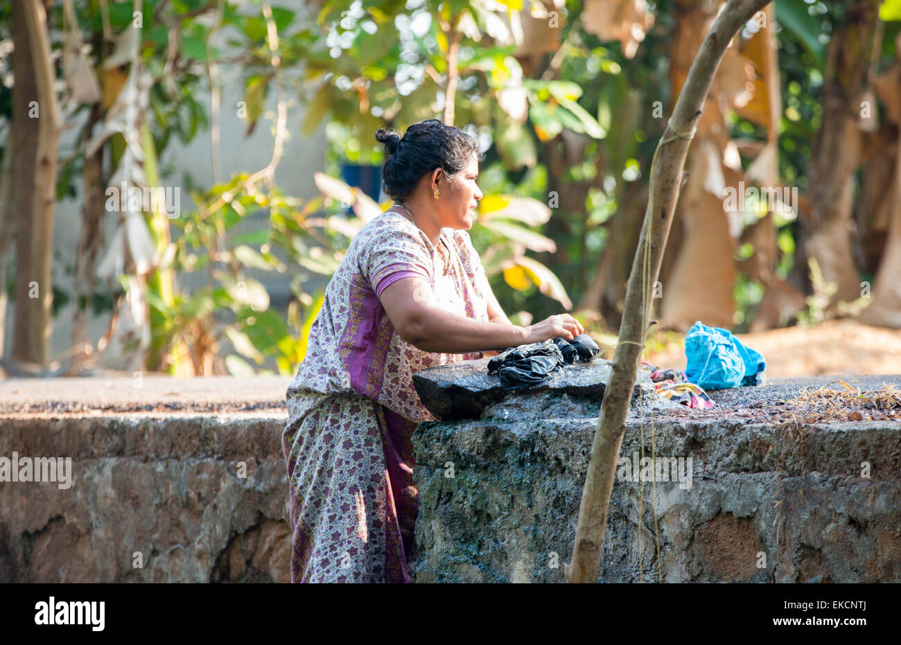 A woman washing her clothes on the banks of the Backwaters of Kumarakom, Kerala India Stock Photo