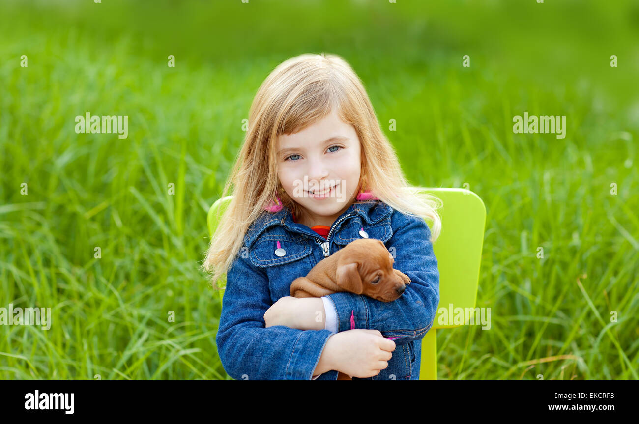 Blond kid girl with puppy pet dog in green grass Stock Photo - Alamy