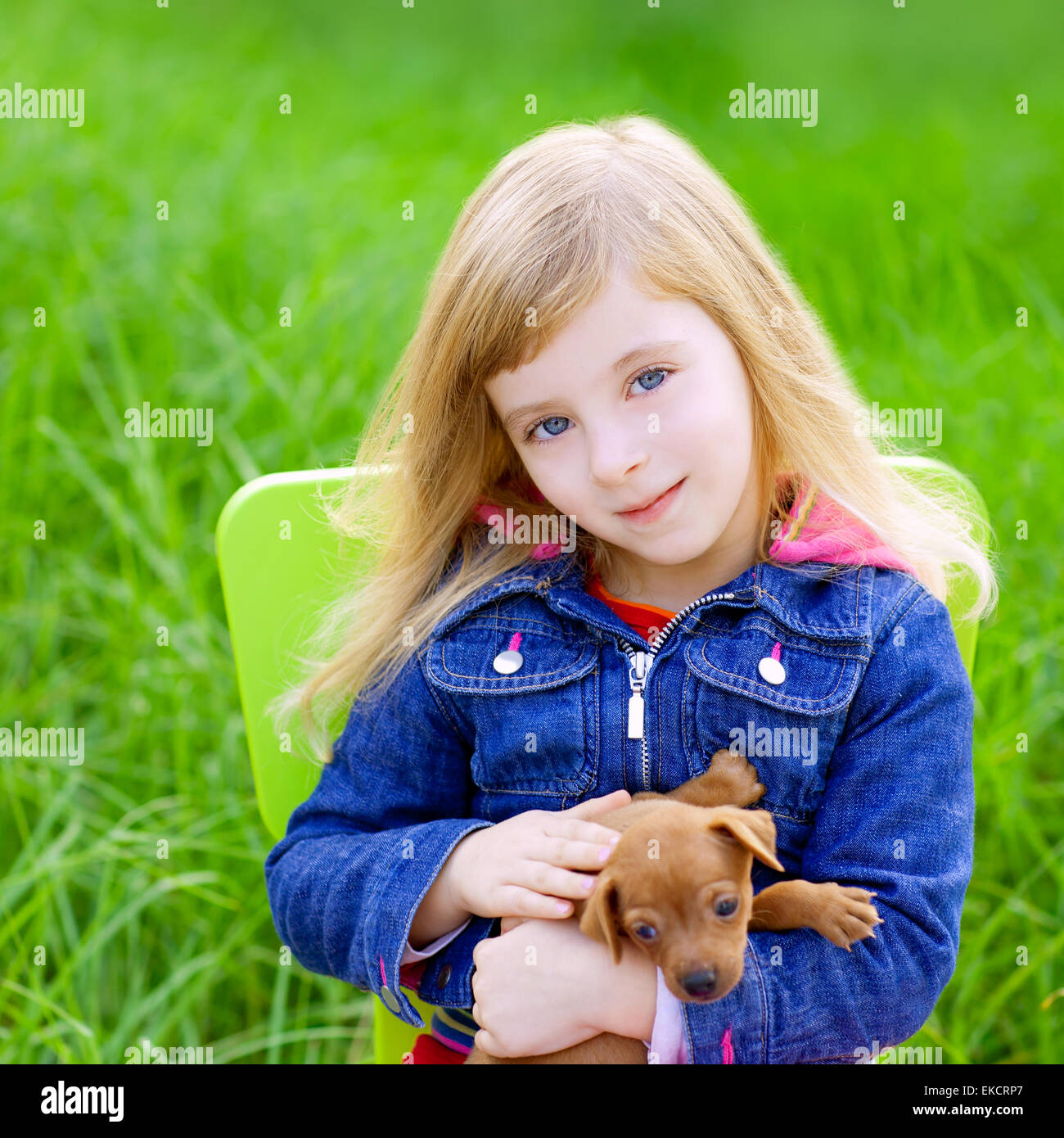 Blond kid girl with puppy pet dog in green grass Stock Photo - Alamy