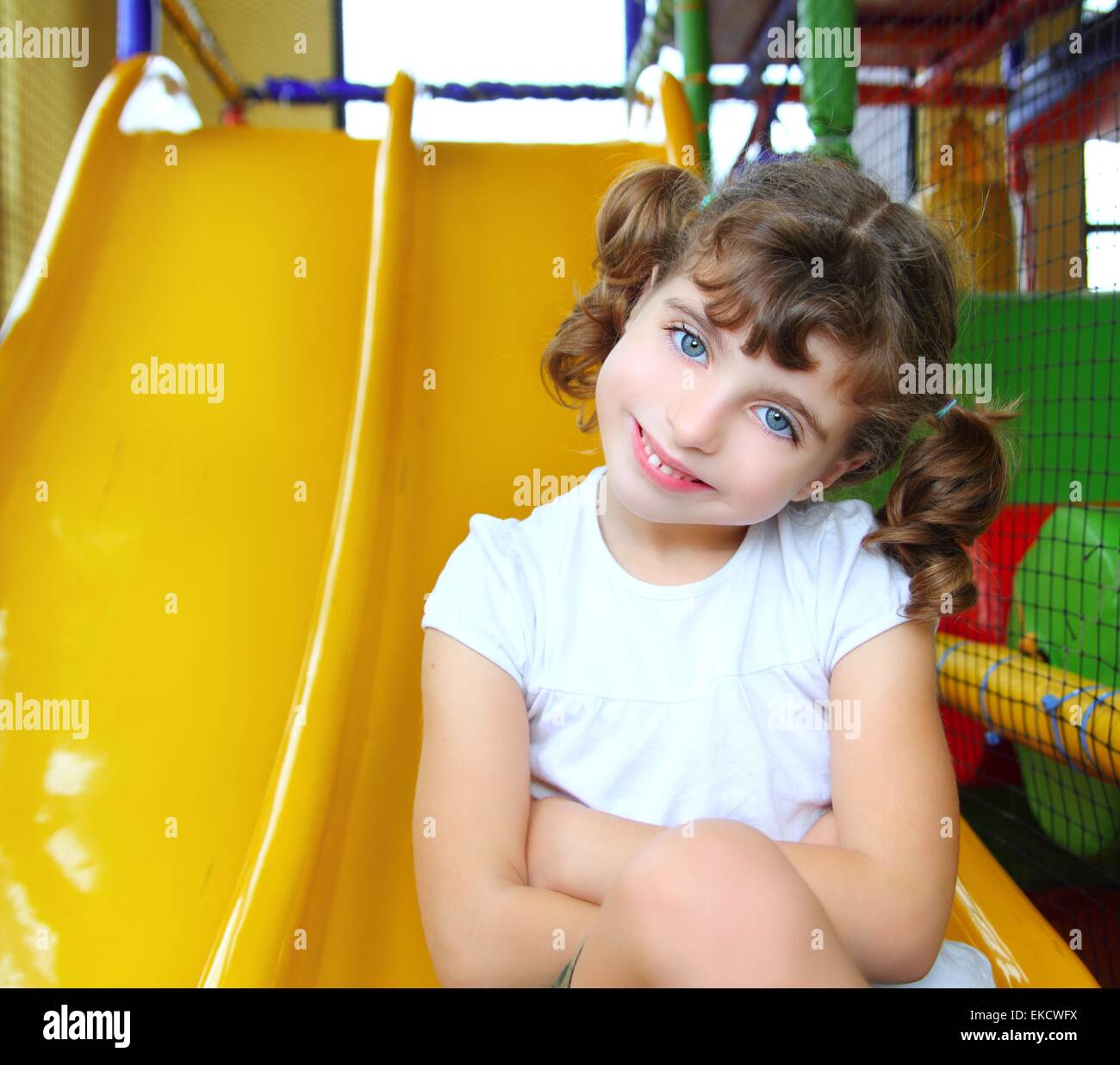 little girl in colorful playground yellow slide Stock Photo - Alamy