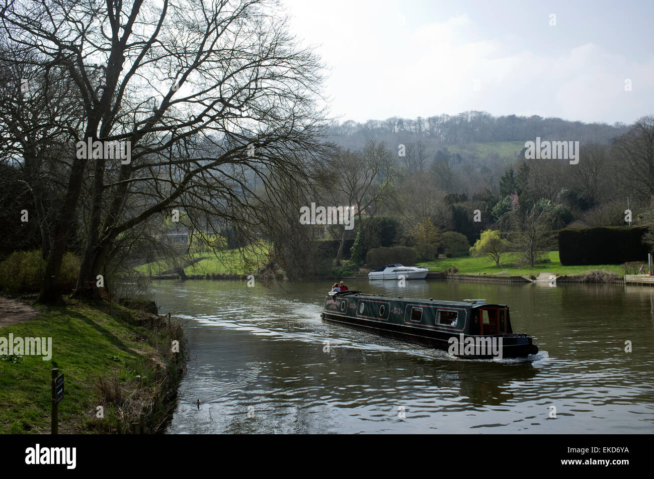 A blue coloured narrow boat (Barge) moving downstream on the River Thames through the Goring Gap, Oxfordshire. Stock Photo
