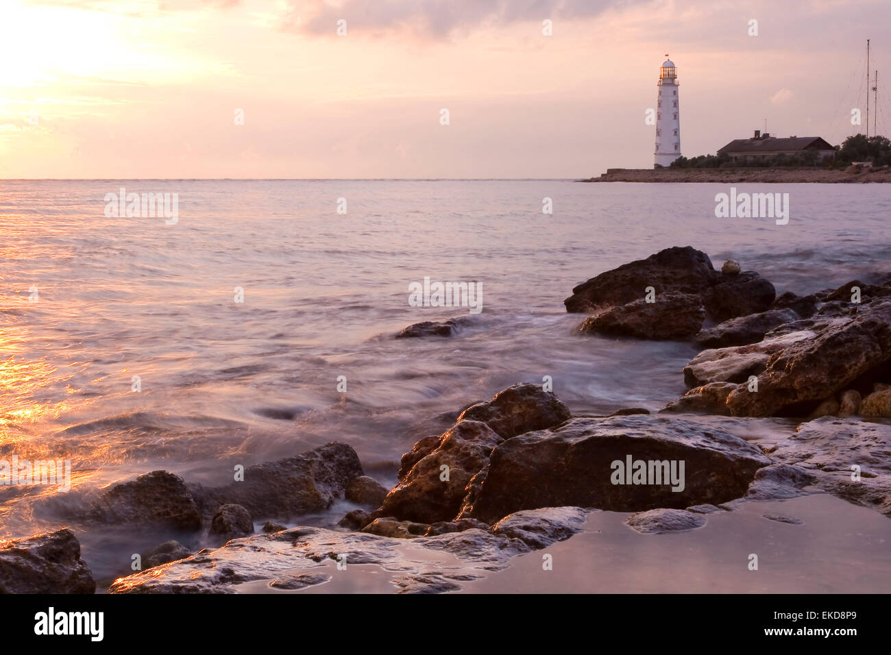 Beautiful rocky sea beach at the sunset with the beacon Stock Photo - Alamy