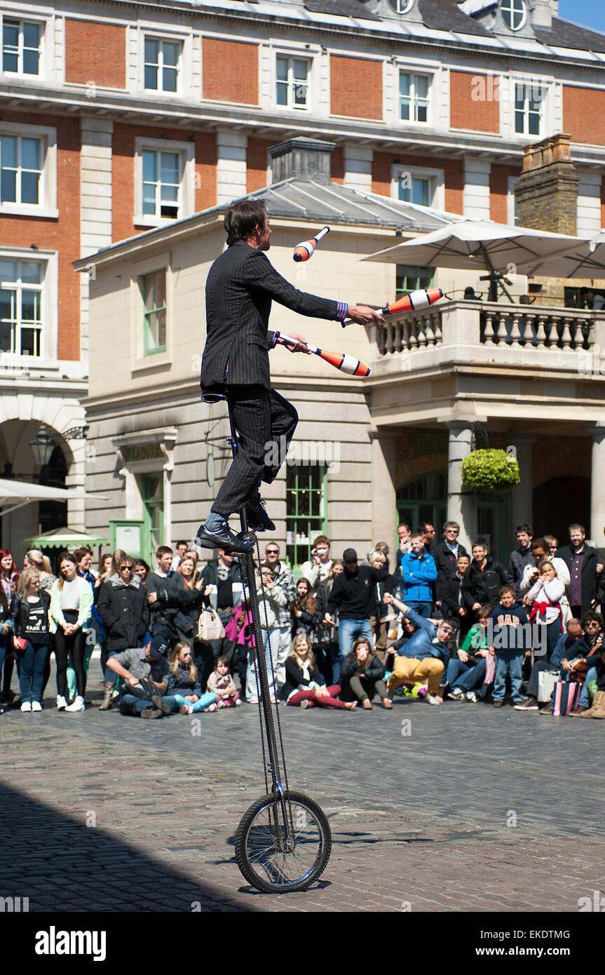 A unicyclist juggling with Indian Clubs to impress the crowds at Covent Garden. Stock Photo