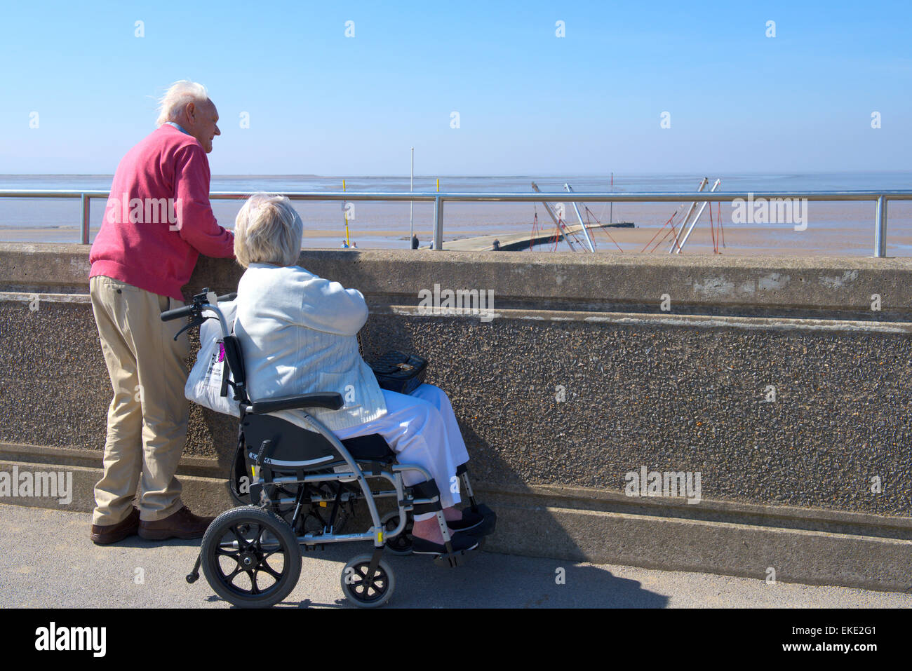 Older couple looking over promenade wall to beach of Burnham-on-Sea, Somerset Stock Photo