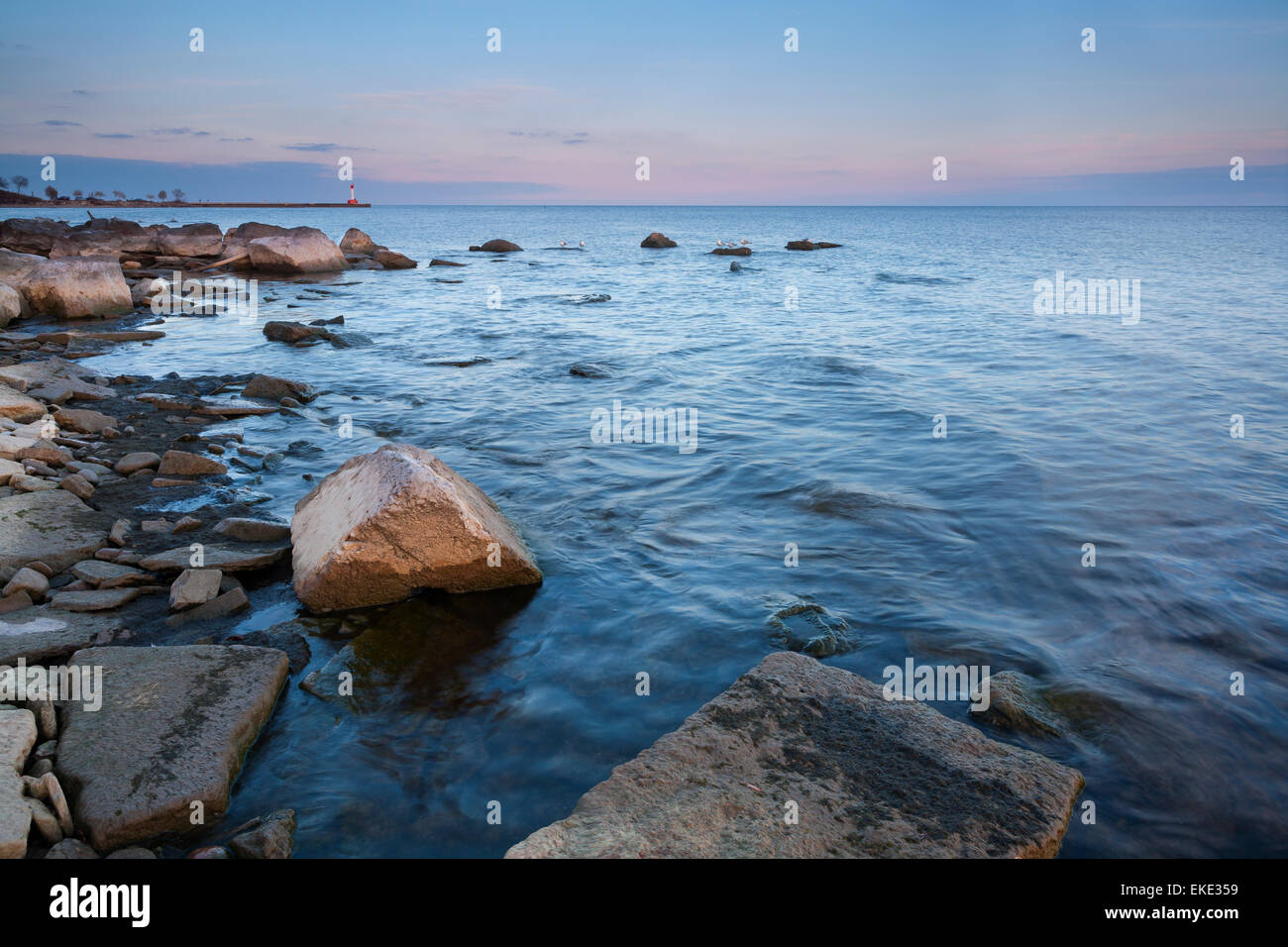 The rocky shoreline of Waterworks Park in Oakville, with a lighthouse in the background. Ontario, Canada. Stock Photo