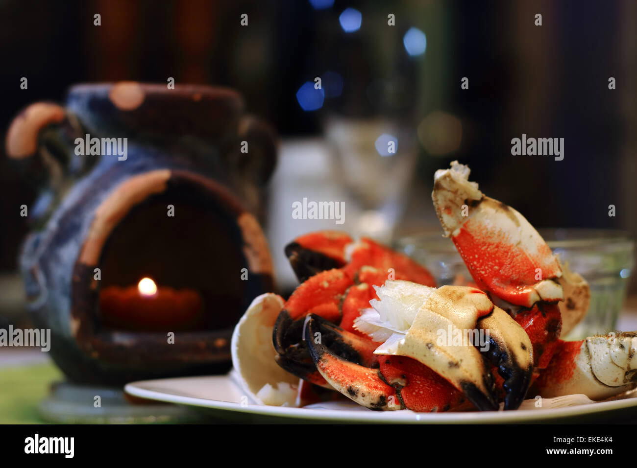 Jonah crab claws showing succulent meat on a plate, with candle light and defocsed flute glass in fine dining settings. Jonah cr Stock Photo