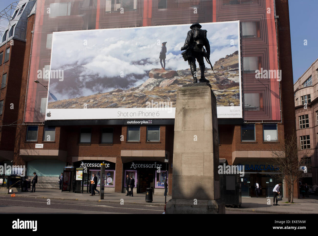 A giant billboard ad for the use of iPhones seen on the side of a central London building, juxtaposed with a WW1 memorial soldier of the Royal Fusiliers. Stock Photo