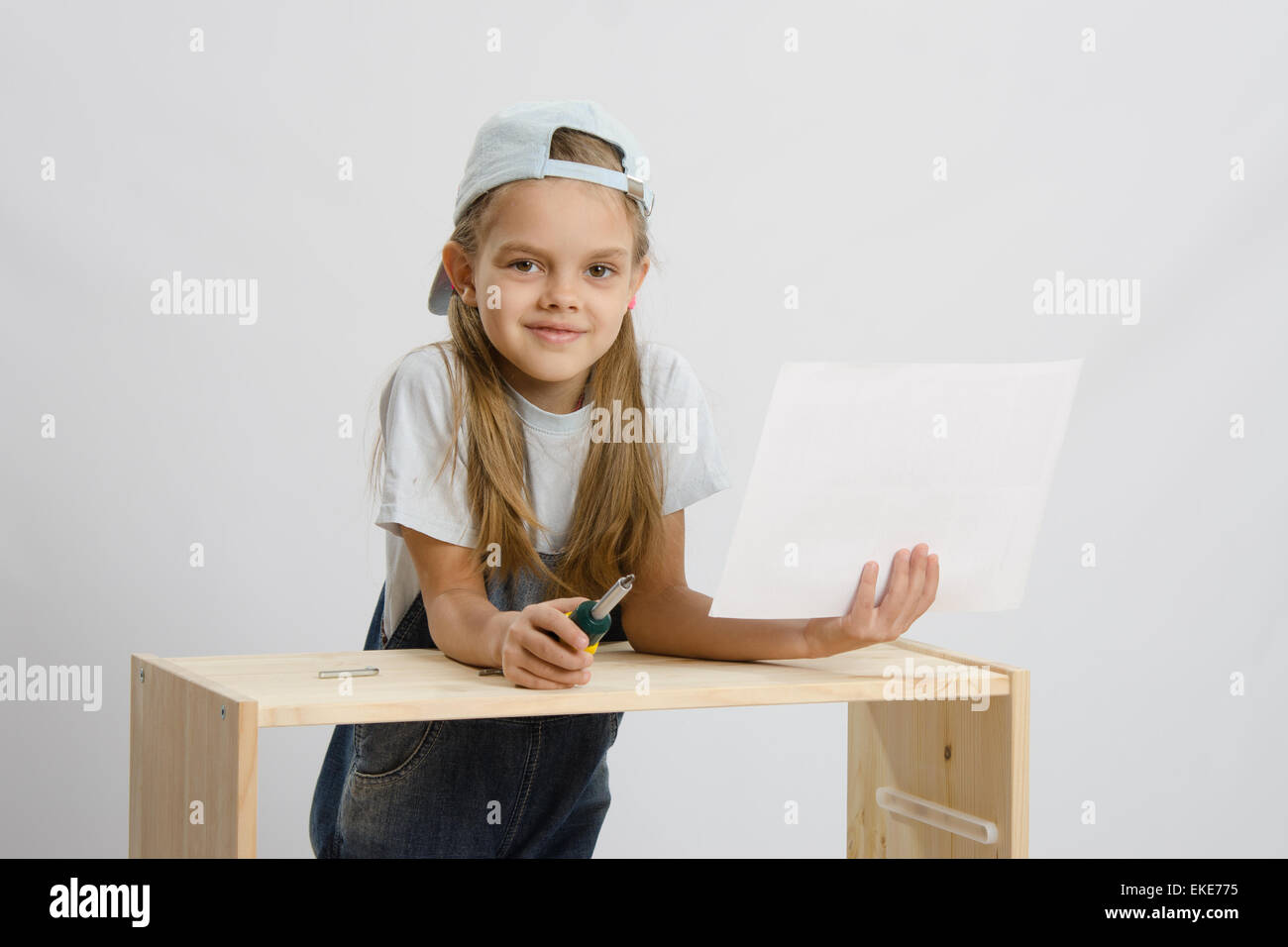 Little girl - collector of furniture with a screwdriver and ...