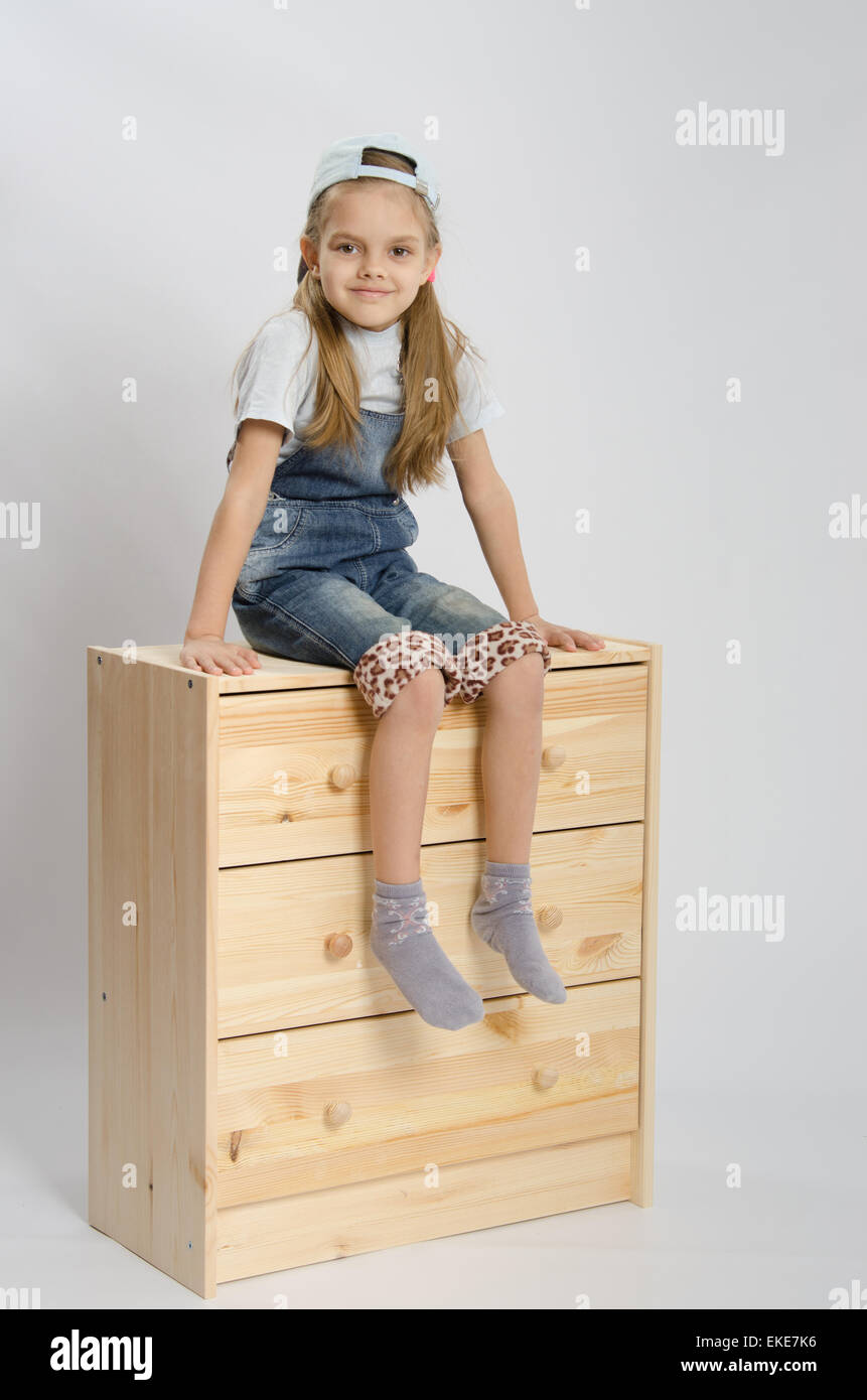 Little Girl Collector Of Furniture In Overalls Relies On A Chest