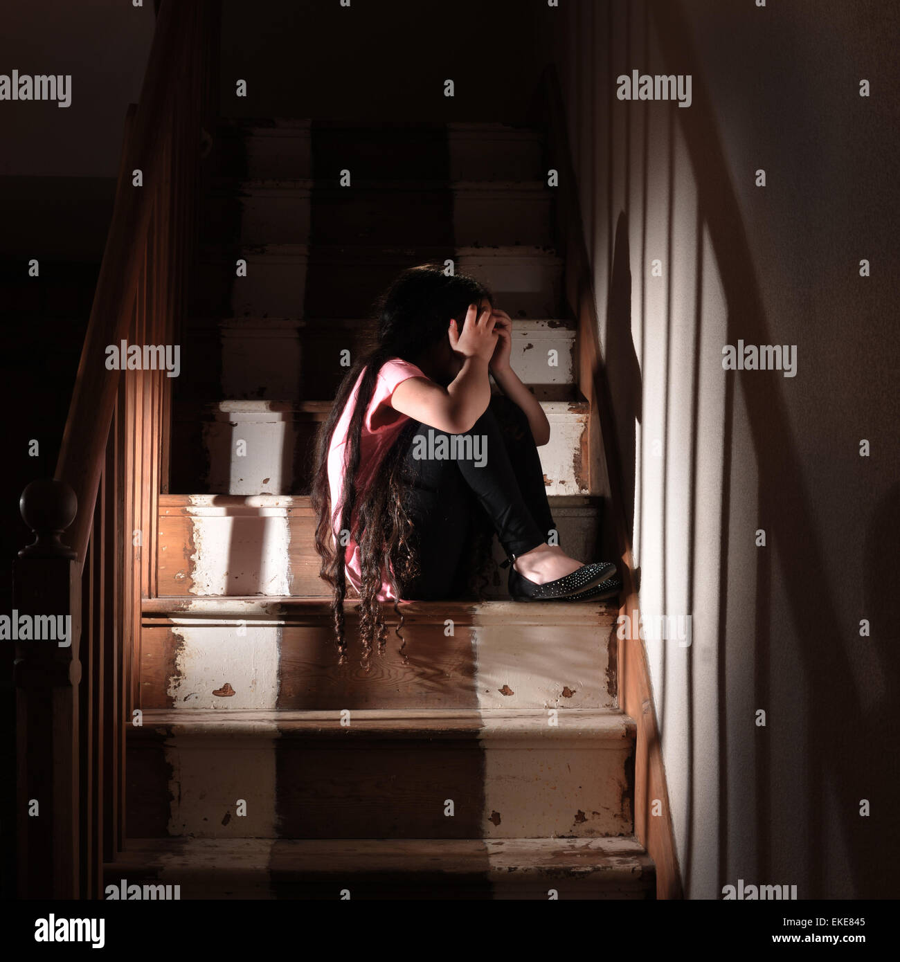 A young child on the stairs at home after suffering abuse. Posed by a model Stock Photo