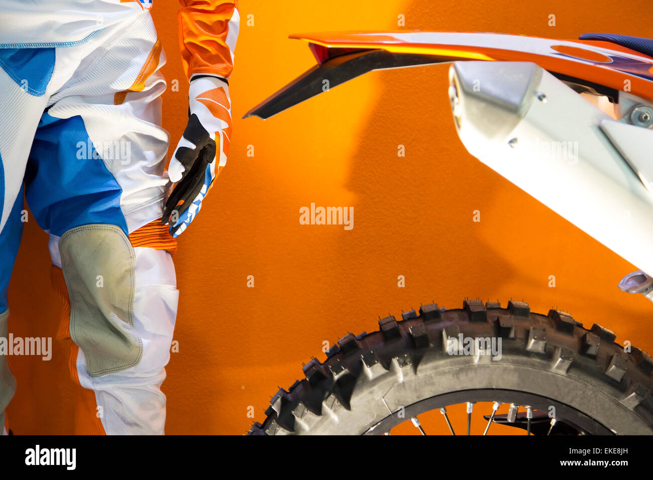 Closeup image of a motocross biker protective clothing and motocross bike on orange background Stock Photo