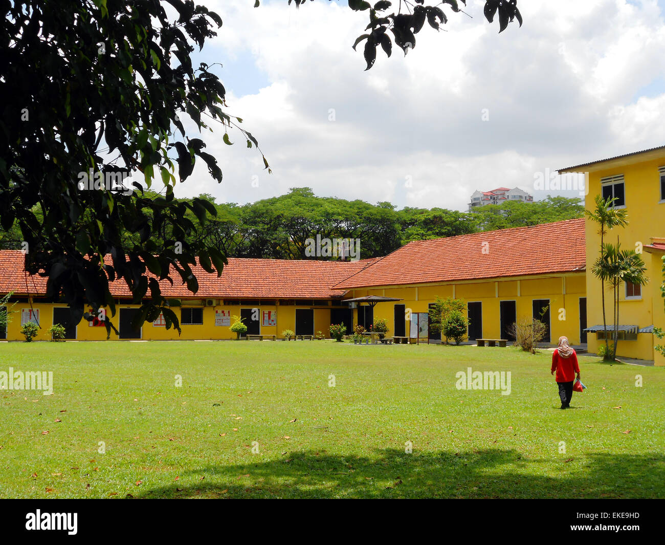 Colorful Schoolyard in Malaysia with a woman walking across the yard Stock Photo