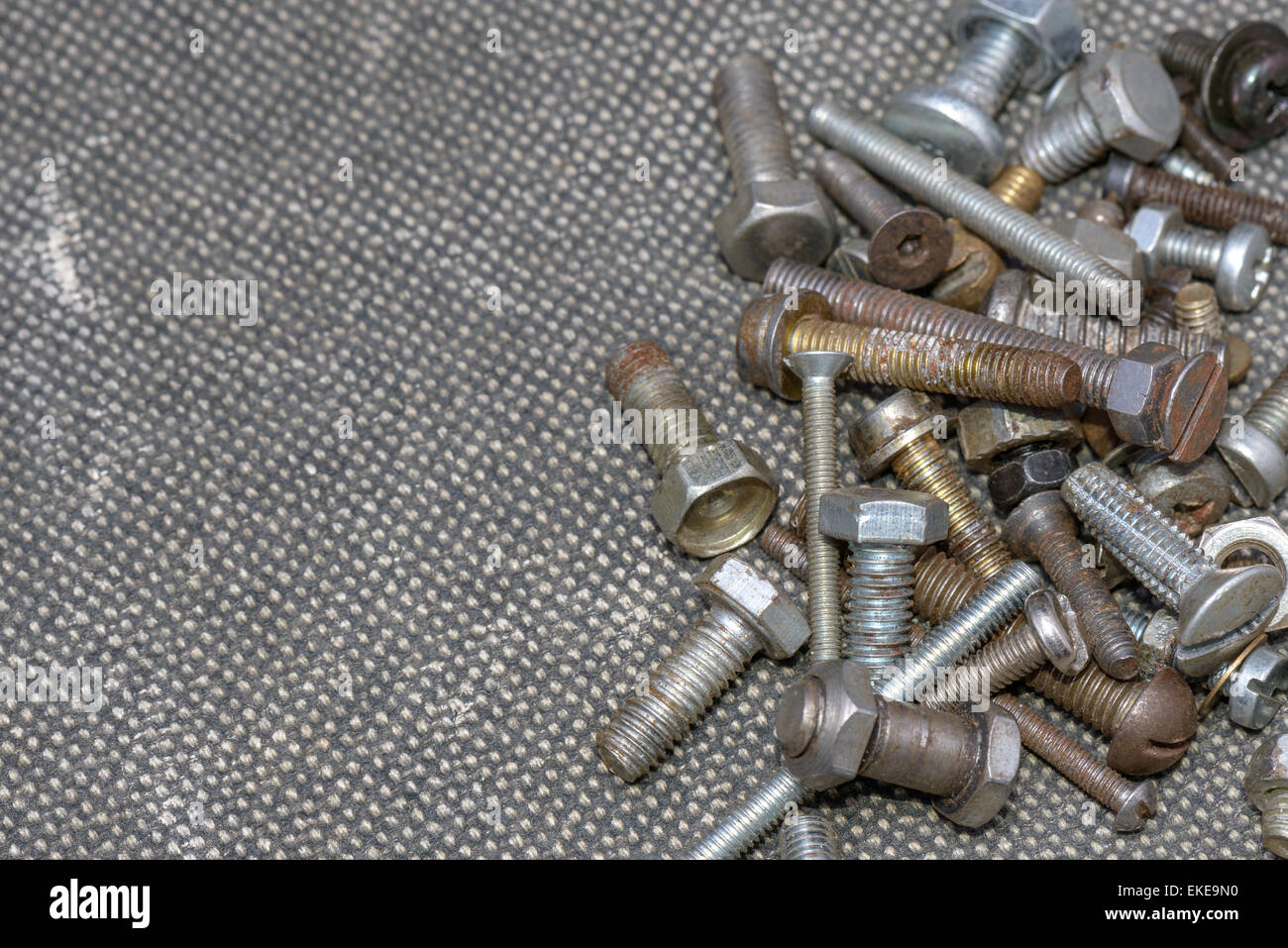 Several old screws on a grey texile background Stock Photo