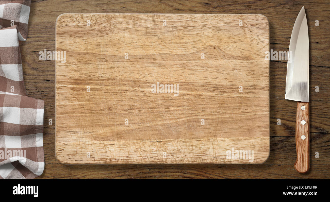 Cutting board and knife on old wood table with picnic tablecloth Stock Photo