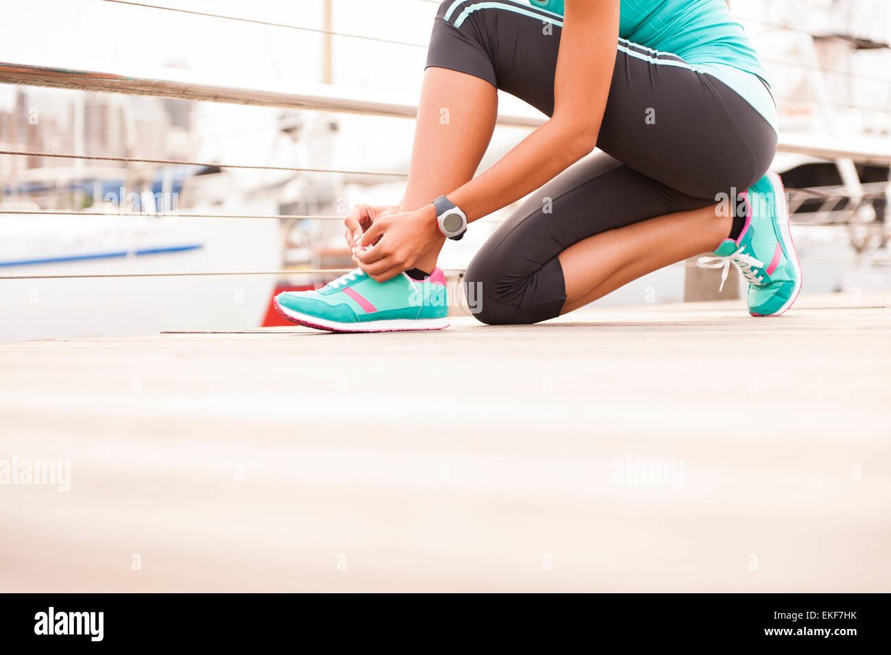 Close up of girl tying her running shoe laces at sunrise Stock Photo